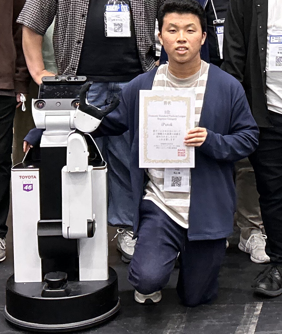 RoboCup 2026 で賞状を持つ松上愉と家庭用サービスロボット HSR